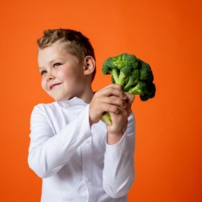 Boy holding head of broccoli                               